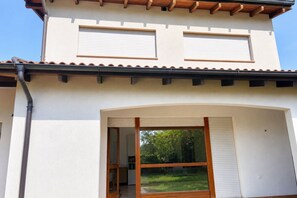 Un bâtiment à deux étages, doté d’un toit plat, d’une grande porte-fenêtre coulissante et d’une porte de garage bien visible.