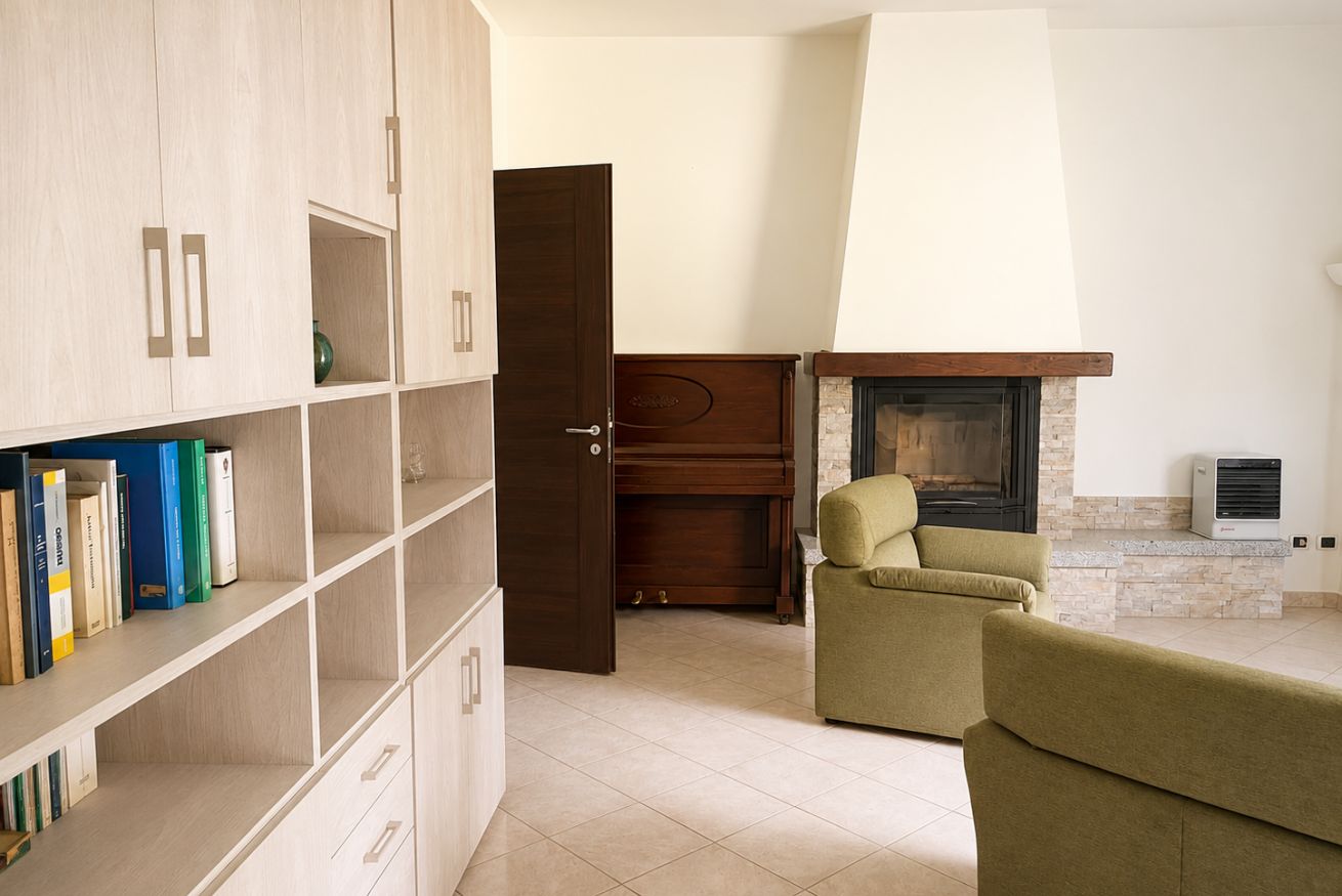 Una sala de estar con chimenea, un sofá, una estantería y una puerta que da a otra habitación.