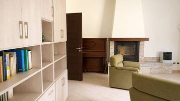 Una sala de estar con chimenea, un sofá, una estantería y una puerta que da a otra habitación.