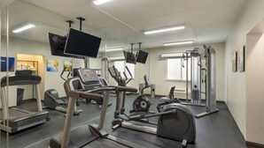 Un gimnasio con cintas de correr, elípticas y equipo de levantamiento de pesas.