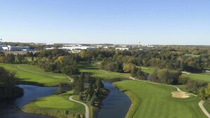 Un campo de golf con obstáculos acuáticos, bunkers de arena y un cielo despejado.