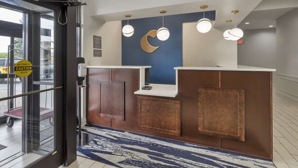 Un mostrador de recepción con pared azul, un adorno con forma de luna creciente y tres lámparas colgantes.