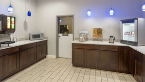 Un área de cocina moderna con cafetera, microondas y refrigerador.