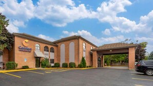 A brick building with a large arched entrance, a sign for Comfort Inn, and a parking lot.