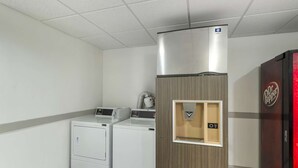 Ein Waschraum mit zwei Waschmaschinen, einem Trockner und einem Kühlschrank.