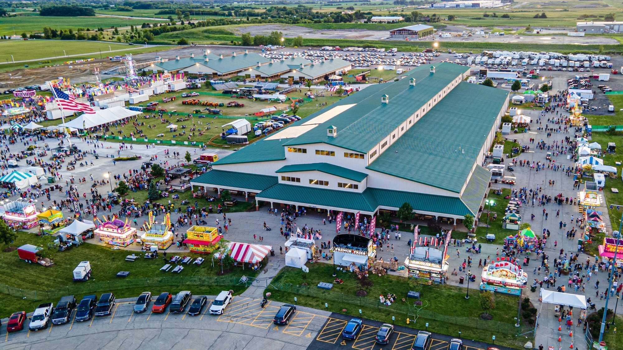 Un grand bâtiment doté d’un toit végétalisé, entouré d’un parking et de diverses attractions en plein air.