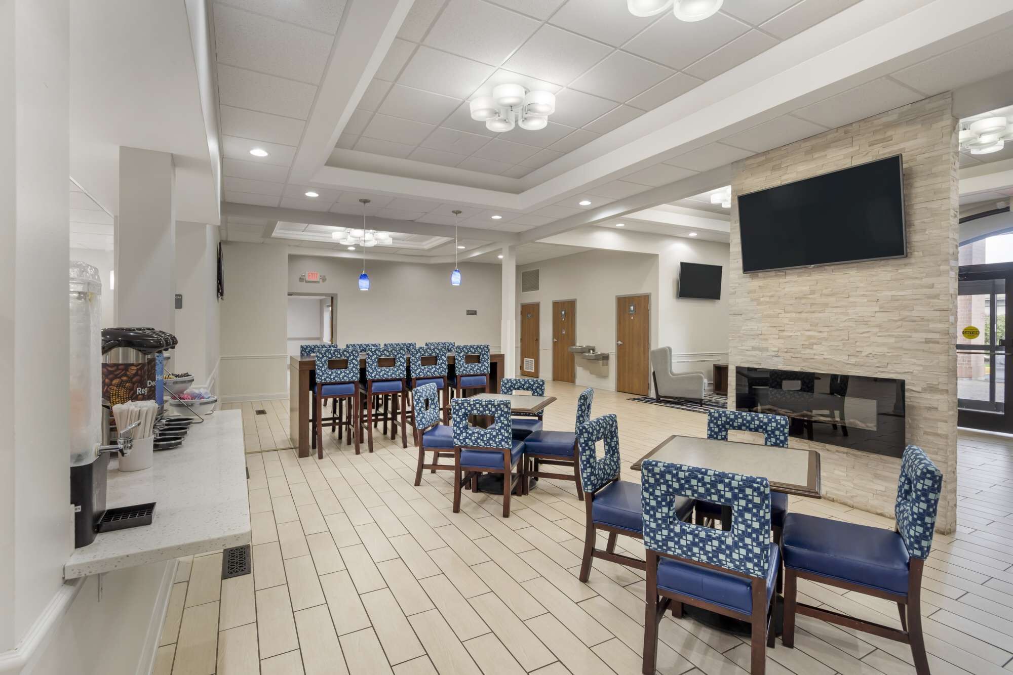 Un grand espace dédié à la salle à manger, avec plusieurs tables et chaises, un coin café et un téléviseur à écran plat fixé au mur.