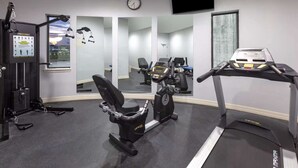 Ein Fitnessstudio mit Trainingsgeräten, Laufband und Spiegelwand.
