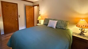 A bedroom with a bed, two nightstands, a lamp, and a door. - Black Bears Crossing- One bed One bath across the road from Sugar Mountain (Banner Elk)