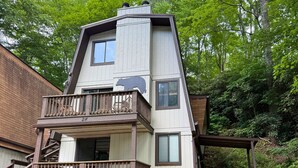 A multi-level house with a balcony, a staircase, and a view of the surrounding forest. - Black Bears Crossing- One bed One bath across the road from Sugar Mountain (Banner Elk)