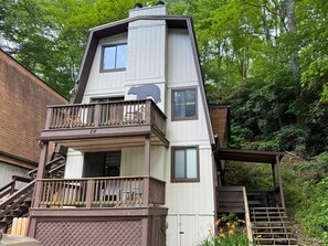 Ein mehrgeschossiges Haus mit Balkon, Treppe und Blick auf den umliegenden Wald.