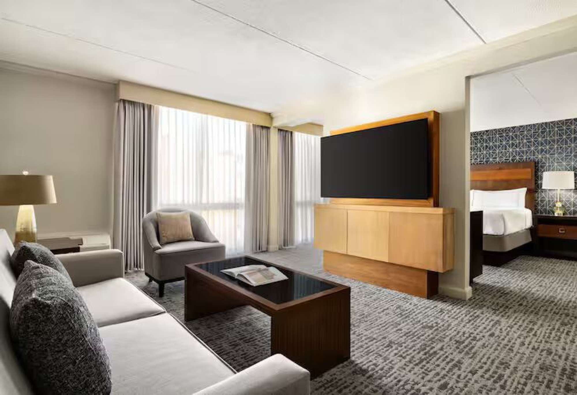 A hotel room with a sofa, a coffee table, a TV, a bed, and a nightstand.