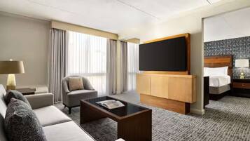 A hotel room with a sofa, a coffee table, a TV, a bed, and a nightstand.