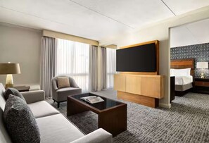 A hotel room with a sofa, a coffee table, a TV, a bed, and a nightstand. - Easy Access To Downtown + Free Parking&Restaurant (Pittsburgh)