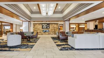 A spacious lobby with a central seating area, a stone accent wall, and a reception desk.