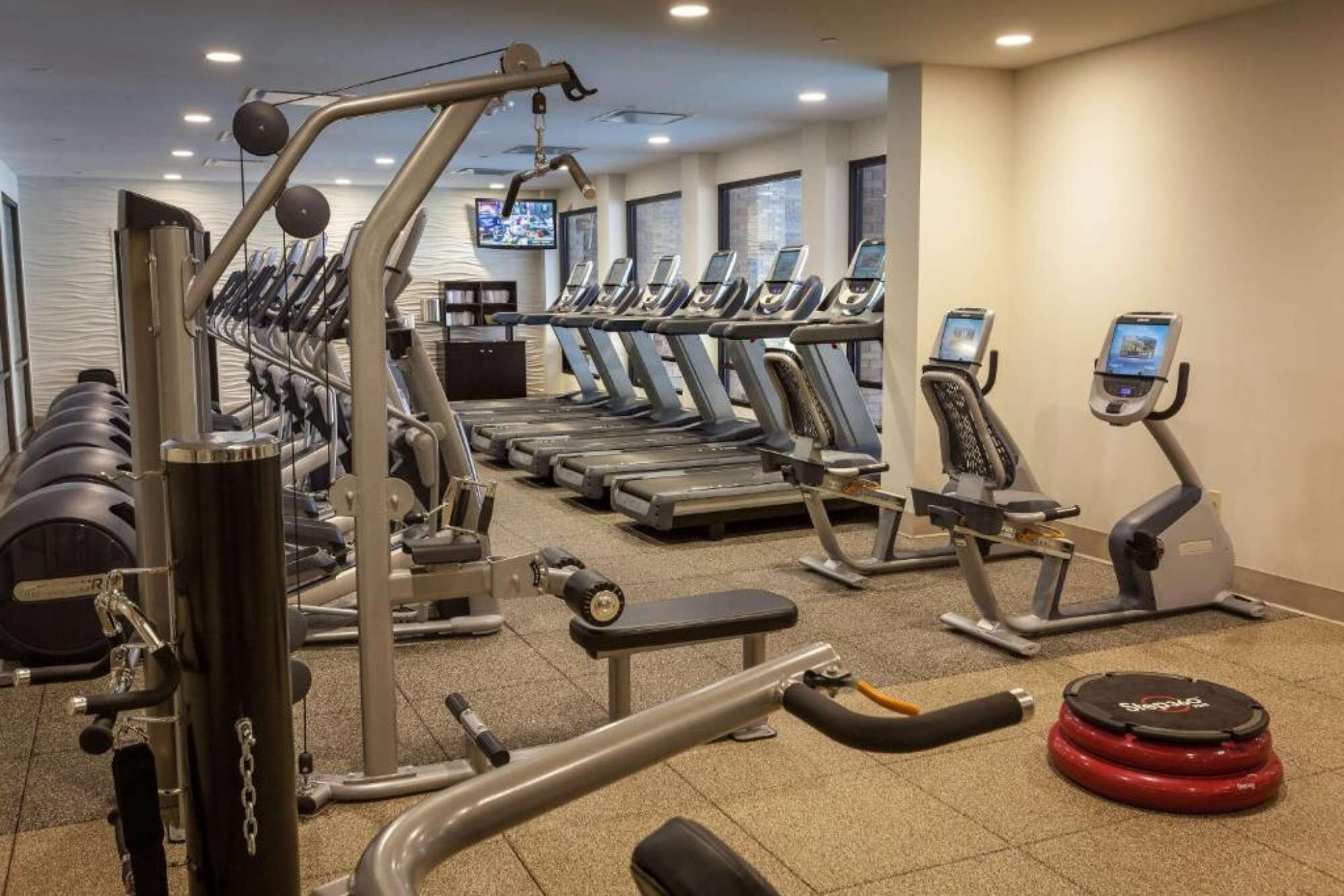 A gym with treadmills, weight machines, and a red exercise ball.