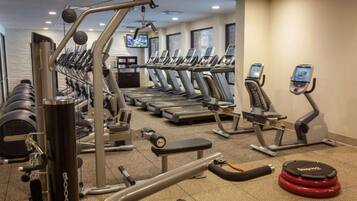 A gym with treadmills, weight machines, and a red exercise ball.