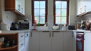 A kitchen with white cabinets, a microwave, a stove, and a window with a view of greenery. - Stunning Private Panorama Suite within a 350m² Luxury Villa – Full Bay View" (Muğla)