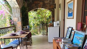 A cozy room with a stone wall, a wooden table with chairs, a rug, and a bookshelf with books and framed pictures. - Stunning Private Panorama Suite within a 350m² Luxury Villa – Full Bay View" (Muğla)