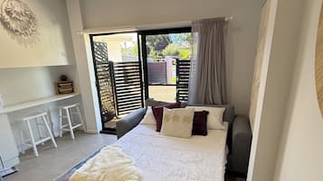 Une chambre à coucher avec un lit, un bureau et une vue sur l’extérieur.