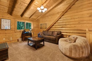 Ein gemütliches Blockhaus-Interieur mit einer Couch, einem Sessel und einem Couchtisch.