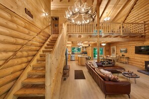 A log cabin interior with a staircase, a dining area, a kitchen, and a living room with a fireplace. - Misty Mountain River House*Fire Pit*Private Cabin (Tillamook)