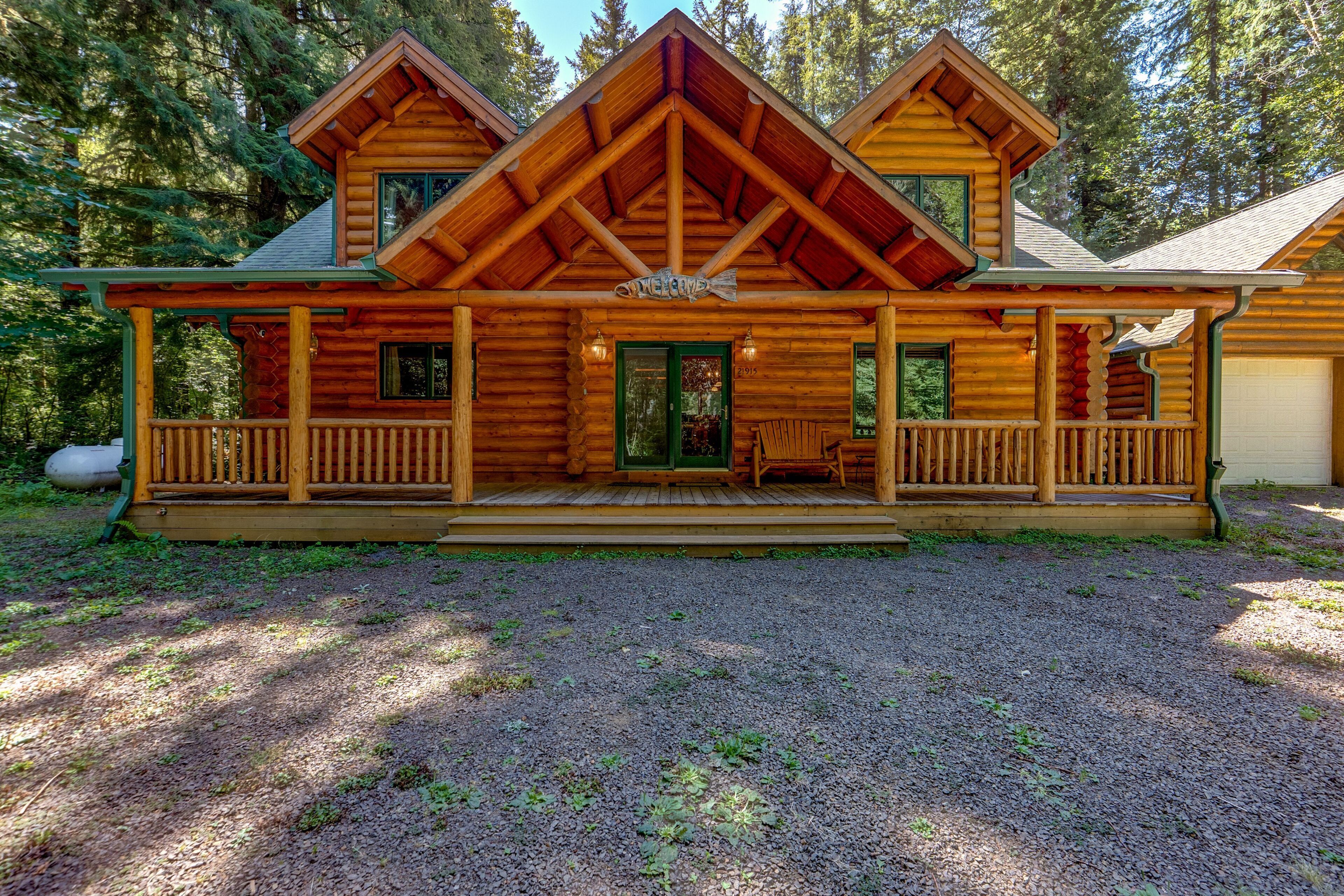 A log cabin with a porch, a front door, and a garage.