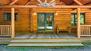 Eine Holzhütte mit Veranda, einem Willkommensschild und einer Bank.