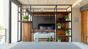 Et værelse med et stort vindue, en sofa, et fjernsyn og reoler med planter.