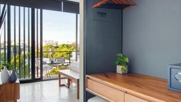 A modern room with a built-in wooden shelf, a small plant, and a view of the outdoors. - Ocean Boutique Condos (Playa del Carmen)