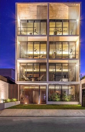 A multi-story building with a modern design, featuring balconies and large windows. - Ocean Boutique Condos (Playa del Carmen)
