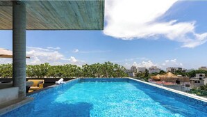 Ein Dachpool mit freiem Blick auf die Stadtlandschaft und Grünflächen im Hintergrund.