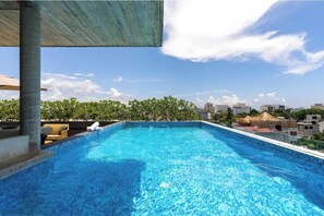 A rooftop swimming pool with a clear view of the city skyline and greenery in the background. - Ocean Boutique Condos (Playa del Carmen)