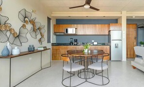 A modern kitchen with wooden cabinets, a microwave, and a refrigerator. - Ocean Boutique Condos (Playa del Carmen)
