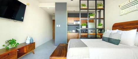 A modern bedroom with a bed, a TV, a ceiling fan, a wooden bench, and a built-in shelving unit with plants.