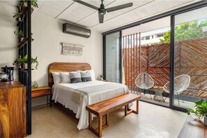 Une chambre à coucher moderne avec un lit en bois, un banc, un ventilateur de plafond, une grande fenêtre et une plante.