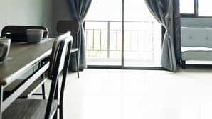 Ein Zimmer mit Esstisch, Stühlen und Blick durch große, mit Vorhängen versehene Fenster.