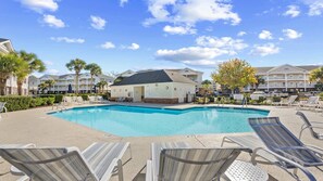 A swimming pool with lounge chairs, a building with a flat roof, and palm trees. - 931 Wedgewood - Barefoot Resort Rentals (North Myrtle Beach)