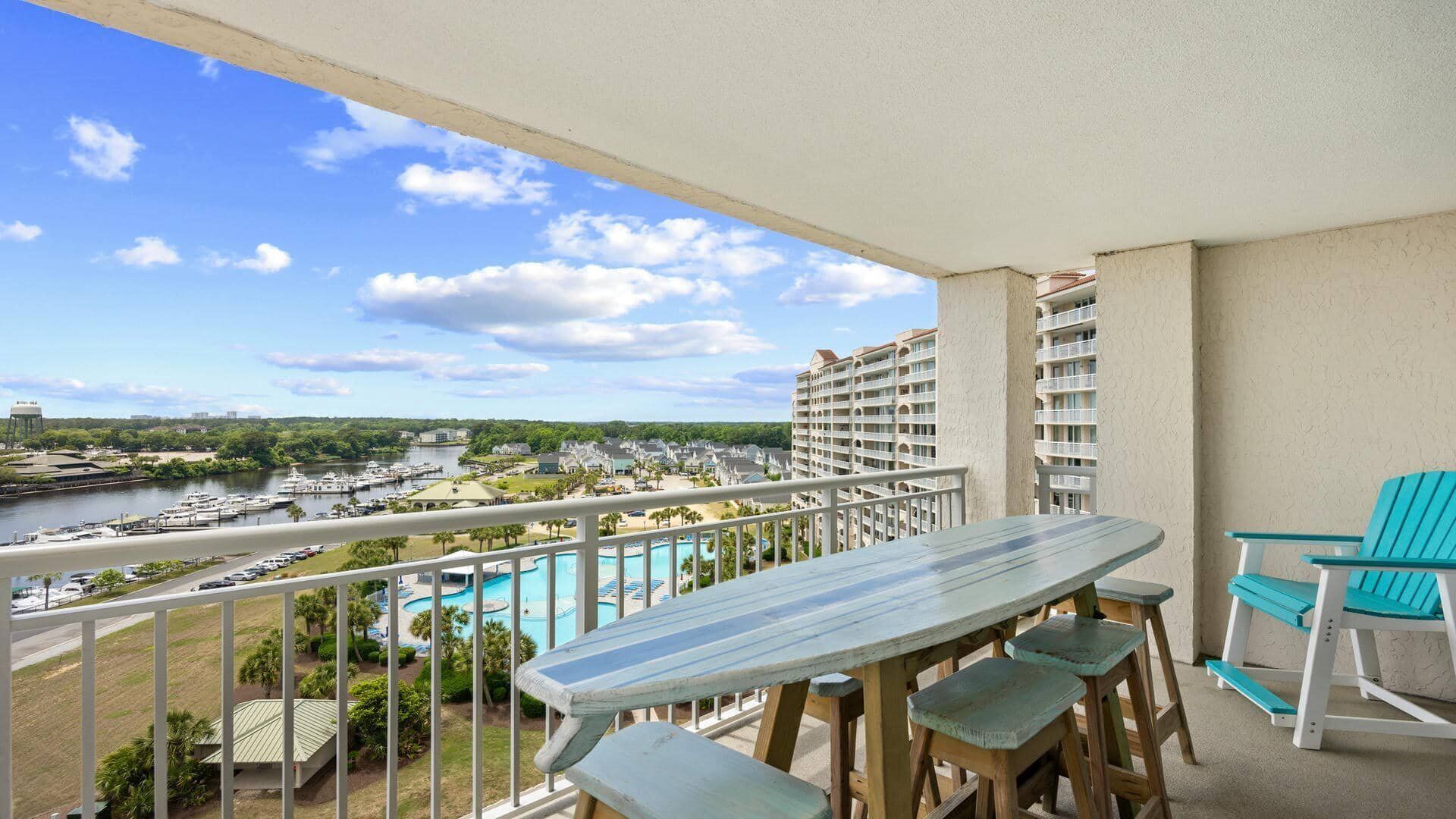 Un balcón con vista a un puerto deportivo, una piscina y un edificio de hotel.