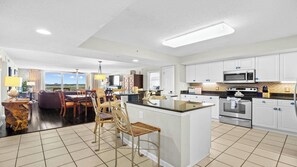 A modern kitchen with white cabinets, stainless steel appliances, and a large island.