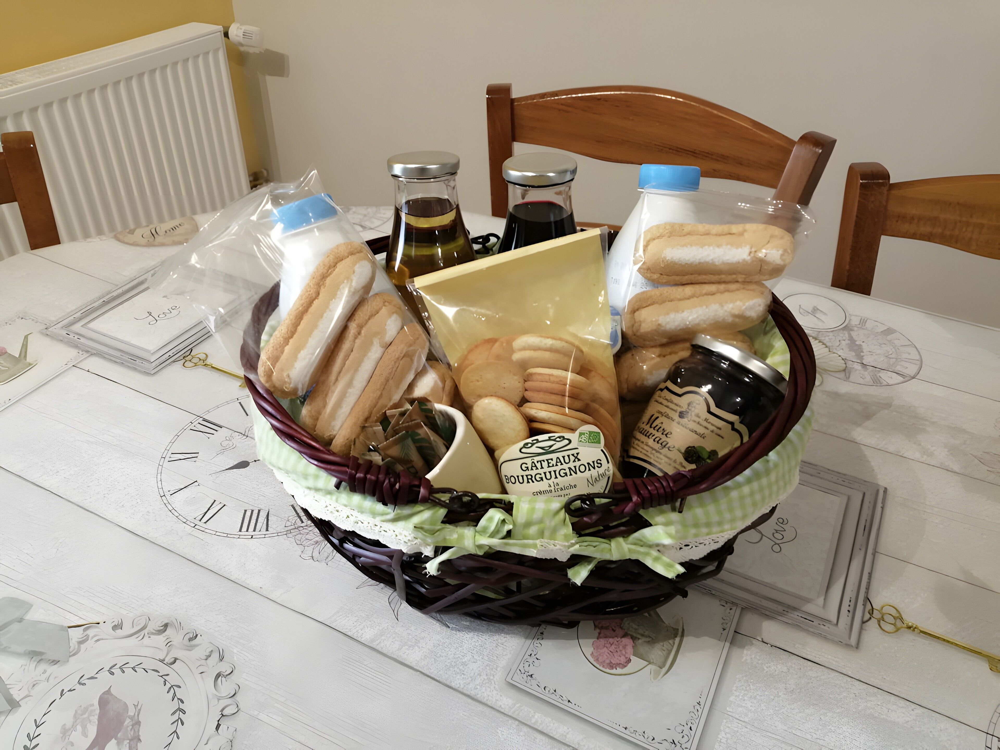 Ein Korbkörbchen voller Lebensmittel und eine Flasche Gâteaux Bourguignons auf einem Tisch mit Uhrendekor.
