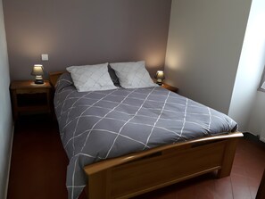 A bedroom with a bed, two bedside lamps, a nightstand, and a window.