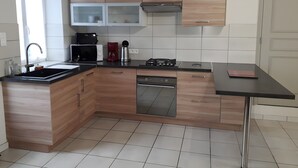 Una cocina moderna con armarios de madera, microondas empotrado, cafetera y estufa a gas.