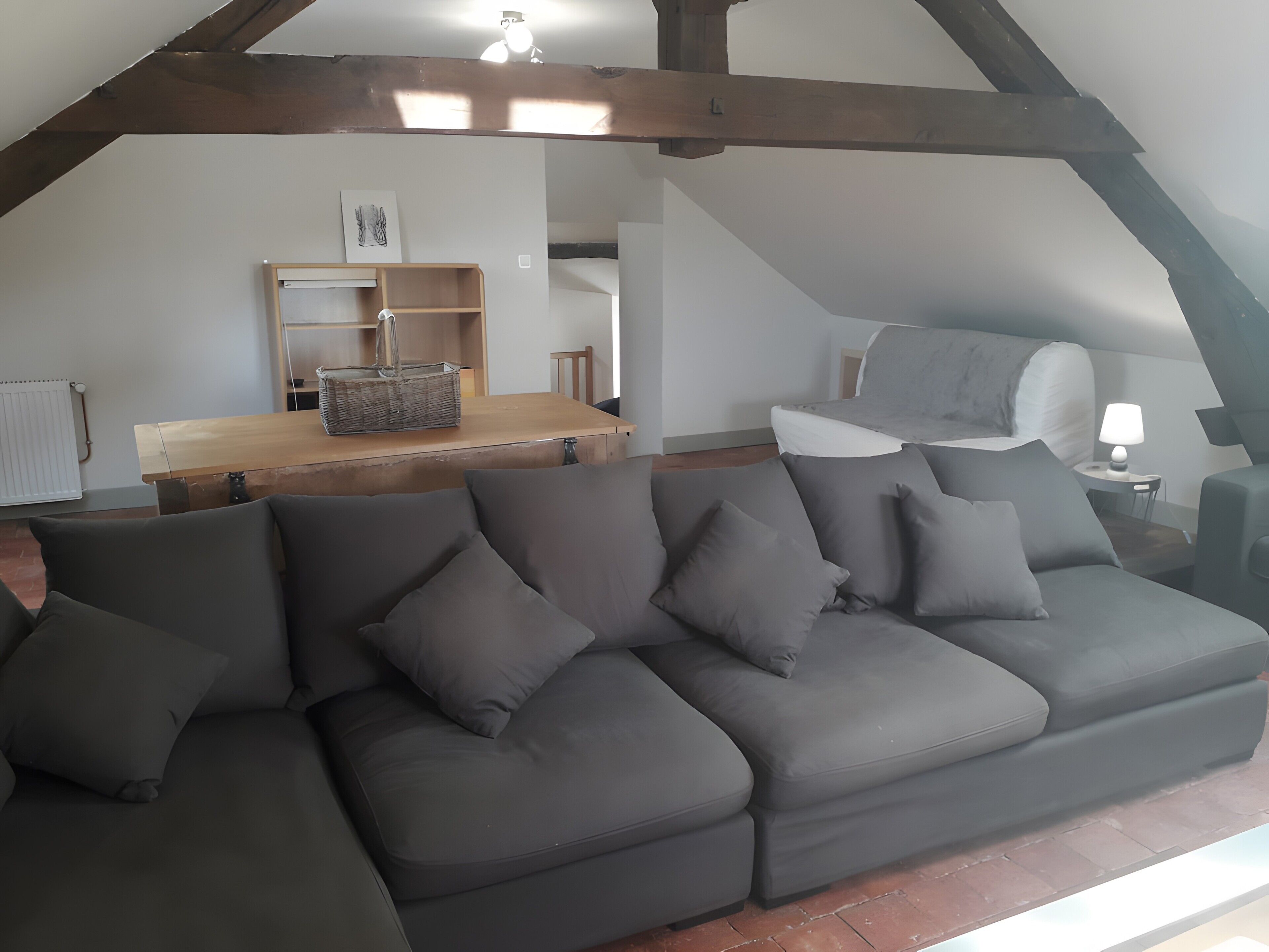 Ein modernes Loft mit einer Eckcouch, einem Esstisch und einem Schlafbett im oberen Bereich.