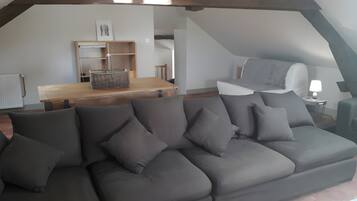Une chambre moderne de style loft, dotée d’un canapé d’angle, d’une table à manger et d’un lit en mezzanine.