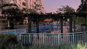 A pool area with a pergola, surrounded by a fence and palm trees. - Fully equipped apartment (Riocentro / Olympic Park) (Rio de Janeiro)