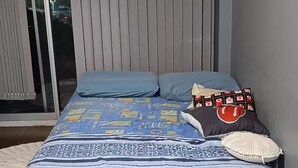 A bedroom with a bed, a window with blinds, a wall-mounted air conditioner, and a door. - Fully equipped apartment (Riocentro / Olympic Park) (Rio de Janeiro)