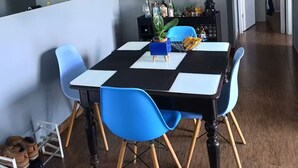 A dining area with a checkered table, blue chairs, and a vase with flowers. - Fully equipped apartment (Riocentro / Olympic Park) (Rio de Janeiro)