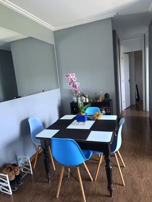 A dining area with a checkered table, blue chairs, and a vase with flowers. - Fully equipped apartment (Riocentro / Olympic Park) (Rio de Janeiro)