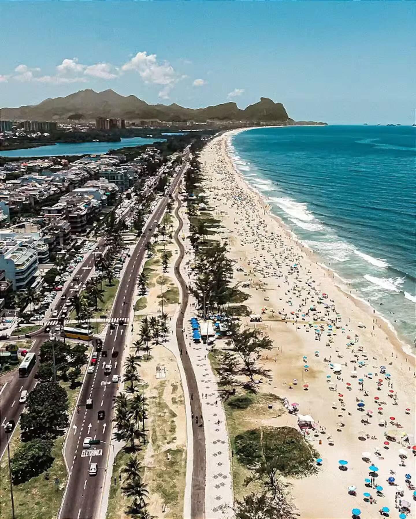 A coastal road with a beach on one side and a cityscape on the other.
